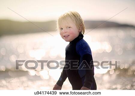 Stock Photo - Boy with wet hair wearing wetsuit, portrait. Fotosearch