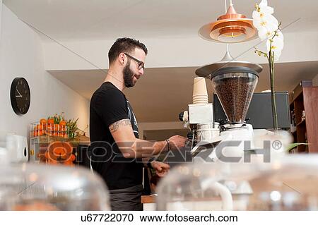 Stock Image - Cafe waiter preparing fresh coffee behind counter. Fotosearch