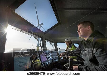 Stock Photo - Captain and mate steer boat through offshore wind farm. Fotosearch
