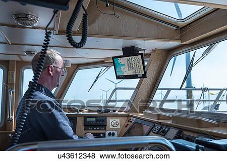 Captain steering service boat at offshore windfarm View Large Photo Image Stock Photo - Captain steering service boat at offshore windfarm. Fotosearch