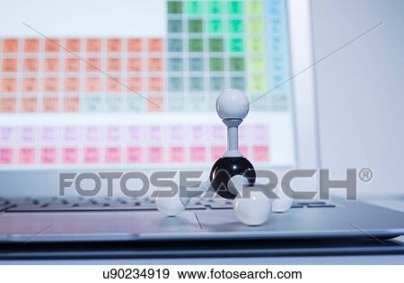 Stock Photo - Chemistry research. A ball-and-stick methane molecule model on a laptop computer displaying periodic table elements. Fotosearch