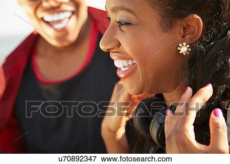 Close up profile of young woman smiling wearing headphones, people in background View Large Photo Image Stock Photo - Close up profile of young woman smiling wearing headphones, people in background. Fotosearch