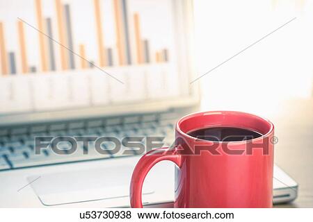 Stock Photo - Close up still life of black coffee and bar finance chart on laptop screen. Fotosearch