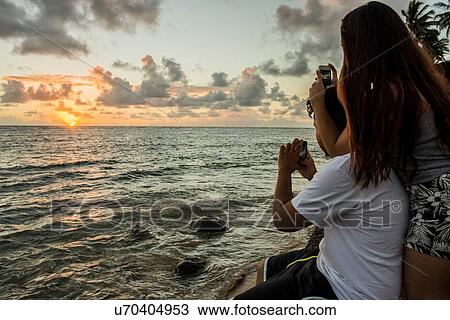 Couple photographing sunrise on smartphones, Kaaawa beach, Oahu, Hawaii, USA View Large Photo Image Stock Image - Couple photographing sunrise on smartphones, Kaaawa beach, Oahu, Hawaii, USA. Fotosearch