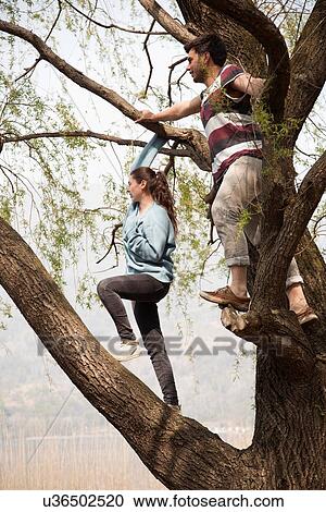 Stock Image - Couple standing in tree looking out over lake Mergozzo, Verbania, Piemonte, Italy. Fotosearch