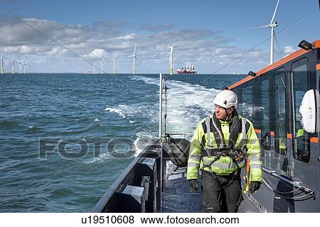 Stock Photo - Crew member on deck of boat on offshore wind farm. Fotosearch