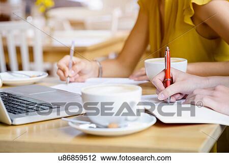 Cropped close up of two young women in cafe writing notes View Large Photo Image Stock Image - Cropped close up of two young women in cafe writing notes. Fotosearch