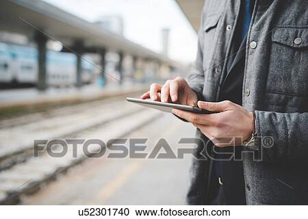 Cropped image of a young businessman commuter 's hands using digital tablet at train station. View Large Photo Image Stock Image - Cropped image of a young businessman commuter 's hands using digital tablet at train station.. Fotosearch