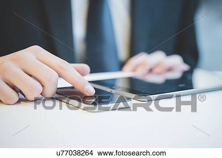 Cropped image of hands of young businessman using digital tablet and mobile phone. View Large Photo Image Picture - Cropped image of hands of young businessman using digital tablet and mobile phone.. Fotosearch