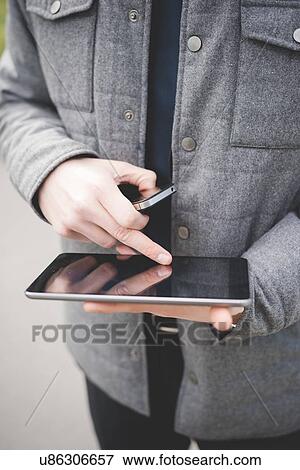 Cropped image of hands of young businessman using digital tablet and mobile phone. View Large Photo Image Stock Photo - Cropped image of hands of young businessman using digital tablet and mobile phone.. Fotosearch