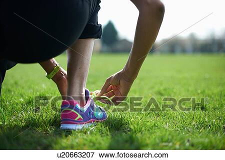 Cropped rear view of mature woman tying trainer laces in park View Large Photo Image Stock Photo - Cropped rear view of mature woman tying trainer laces in park. Fotosearch