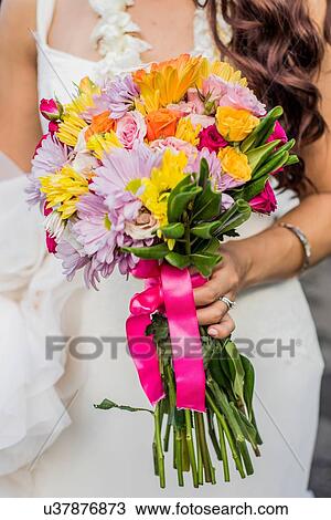 Stock Image - Cropped view of bride and colorful boquet at Hawaiian wedding, Kaaawa, Oahu, Hawaii, USA. Fotosearch