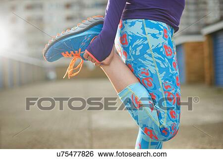 Stock Photograph - Cropped view of woman bending leg and stretching before exercise. Fotosearch