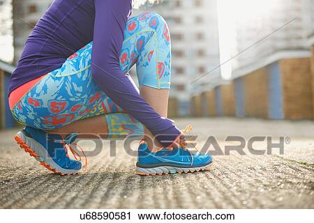 Cropped view of woman bending to tie sports training shoe lace View Large Photo Image Stock Image - Cropped view of woman bending to tie sports training shoe lace. Fotosearch