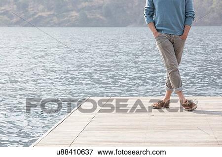 Stock Photo - Cropped view of young man standing on pier, Lake Mergozzo, Verbania, Piemonte, Italy. Fotosearch