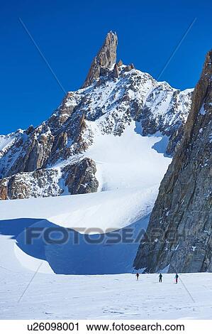 Stock Image - Distant view of three skiers on Mont Blanc massif, Graian Alps, France. Fotosearch