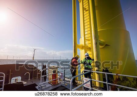 Engineers climbing wind turbine at offshore wind farm View Large Photo Image Stock Photo - Engineers climbing wind turbine at offshore wind farm. Fotosearch