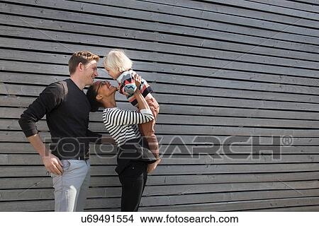 Family by clapboard wall, mother holding son View Large Photo Image Picture - Family by clapboard wall, mother holding son. Fotosearch