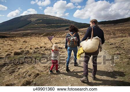 Stock Image - Family hiking on path in hills, Fairy Pools, Isle of Skye, Hebrides, Scotland. Fotosearch
