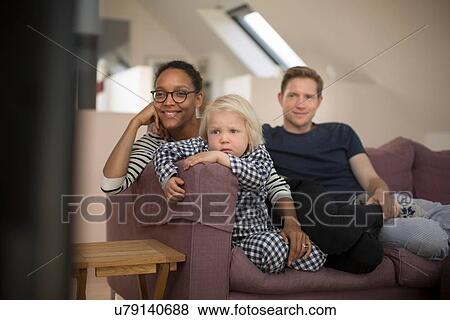 Stock Photo - Family sitting on sofa watching television. Fotosearch