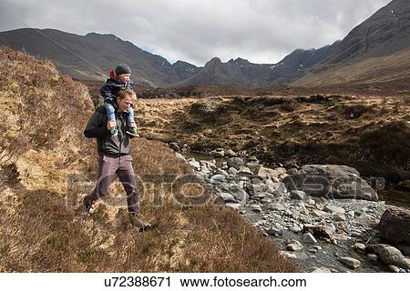 Stock Image - Father and son hiking, Fairy Pools, Isle of Skye, Hebrides, Scotland. Fotosearch