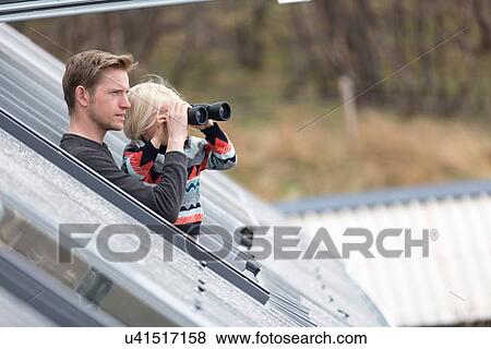 Stock Photo - Father and son looking through rooflight, boy using binoculars. Fotosearch