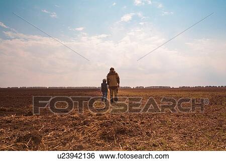 Father and son standing together in field, rear view View Large Photo Image Stock Photograph - Father and son standing together in field, rear view. Fotosearch