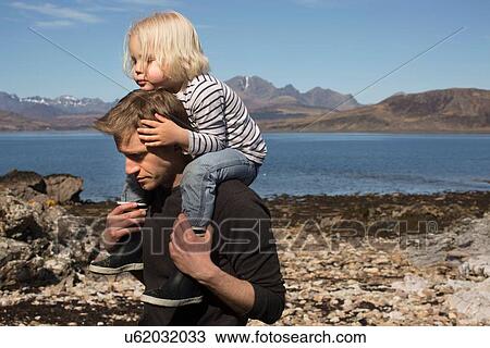 Stock Image - Father carrying son on shoulders, Loch Eishort, Isle of Skye, Hebrides, Scotland. Fotosearch