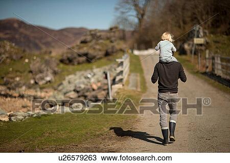Father carrying son on shoulders, walking on path, rear view View Large Photo Image Stock Image - Father carrying son on shoulders, walking on path, rear view. Fotosearch