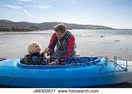 Stock Photo - Father helping son in canoe, Loch Eishort, Isle of Skye, Hebrides, Scotland. Fotosearch
