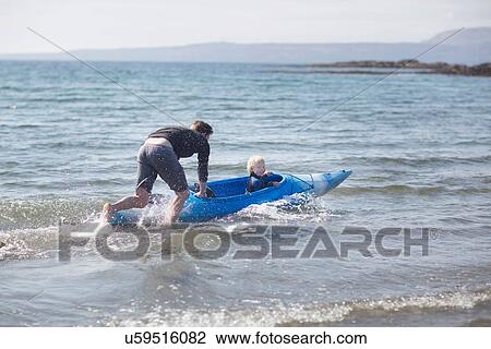 Father pushing son in water in canoe View Large Photo Image Stock Image - Father pushing son in water in canoe. Fotosearch