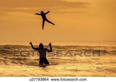Picture - Father throwing son in air, in sea at sunset, Lahinch, Clare, Ireland. Fotosearch
