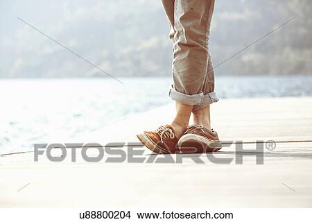 Feet of young man standing on pier, Lake Mergozzo, Verbania, Piemonte, Italy View Large Photo Image Picture - Feet of young man standing on pier, Lake Mergozzo, Verbania, Piemonte, Italy. Fotosearch