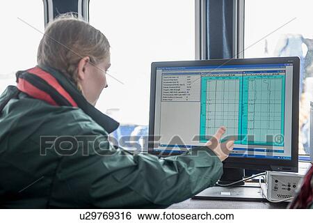 Stock Photograph -  Female scientist inspecting water data on research ship. Fotosearch