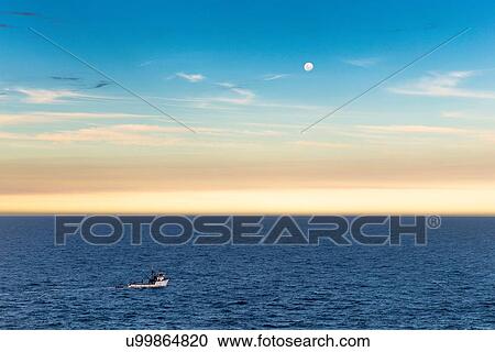 Stock Image - Fishing boat and full moon at dusk, Ponta do Criminoso, Buzios, Rio de Janeiro, Brazil. Fotosearch