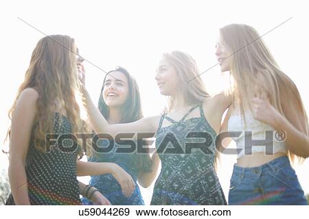 Stock Photo - Four teenage girls chatting in park. Fotosearch