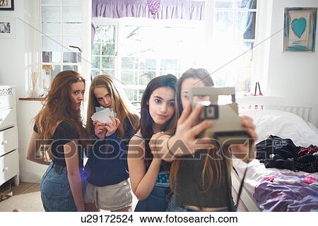Four teenage girls in bedroom taking instant camera selfie View Large Photo Image Picture - Four teenage girls in bedroom taking instant camera selfie. Fotosearch