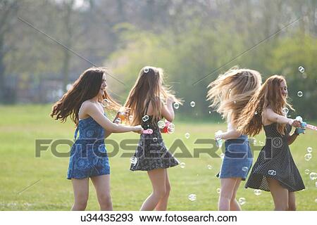 Four teenage girls spinning bubbles with bubble wand in park View Large Photo Image Stock Image - Four teenage girls spinning bubbles with bubble wand in park. Fotosearch