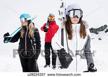Friends wearing helmets and ski goggles holding skis, portrait View Large Photo Image Stock Photo - Friends wearing helmets and ski goggles holding skis, portrait. Fotosearch