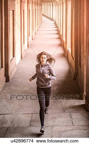 Front view of young woman wearing sports clothes jogging View Large Photo Image Picture - Front view of young woman wearing sports clothes jogging. Fotosearch