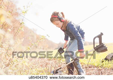 Girl crouching with spade and metal detector in field View Large Photo Image Stock Image - Girl crouching with spade and metal detector in field. Fotosearch