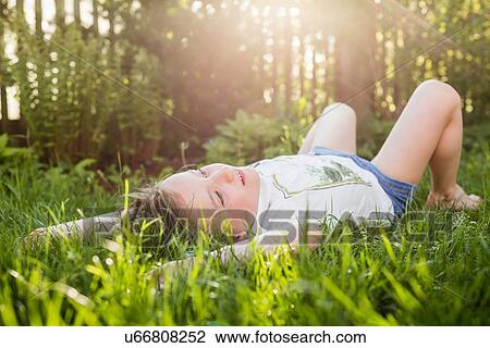Stock Image - Girl lying on grass gazing in garden. Fotosearch