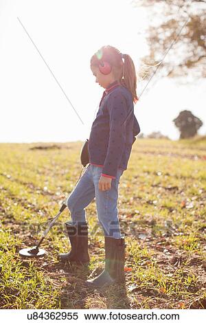Girl wearing headphones using metal detector in field View Large Photo Image Stock Photography - Girl wearing headphones using metal detector in field. Fotosearch
