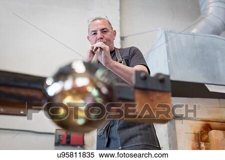 Stock Photography - Glassblower blowing hot glass. Fotosearch