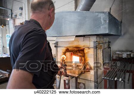 Stock Photography - Glassblower drawing molten glass from furnace. Fotosearch