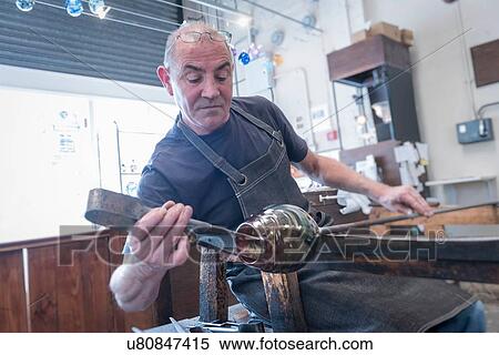 Stock Photography - Glassblower forming hot glass. Fotosearch
