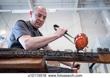 Stock Photo - Glassblower forming molten glass. Fotosearch