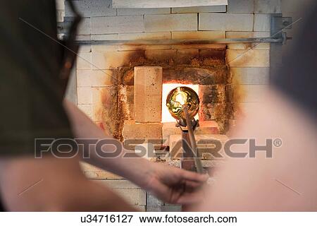 Glassblower heating formed glass in furnace View Large Photo Image Stock Photo - Glassblower heating formed glass in furnace. Fotosearch