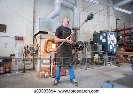 Picture - Glassblower spinning hot glass. Fotosearch