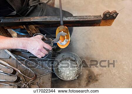 Glassblower using tool to trim molten glass in workshop, close up View Large Photo Image Picture - Glassblower using tool to trim molten glass in workshop, close up. Fotosearch